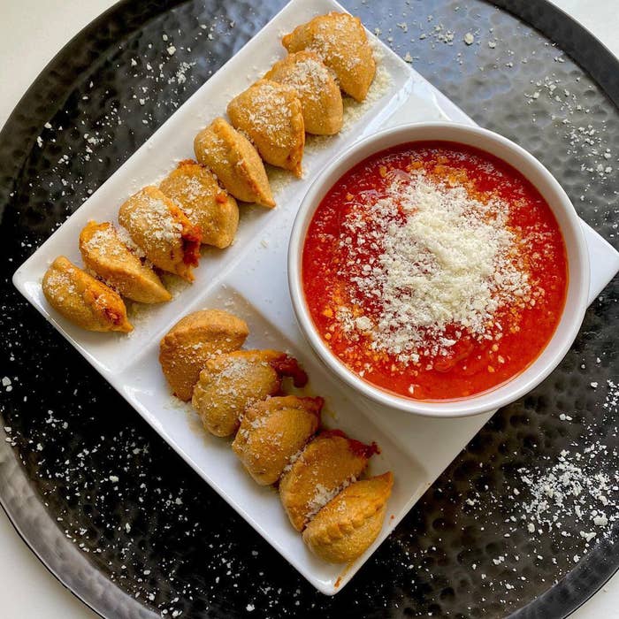 The pizza bites next to a bowl of tomato sauce with cheese sprinkled over the top of everything