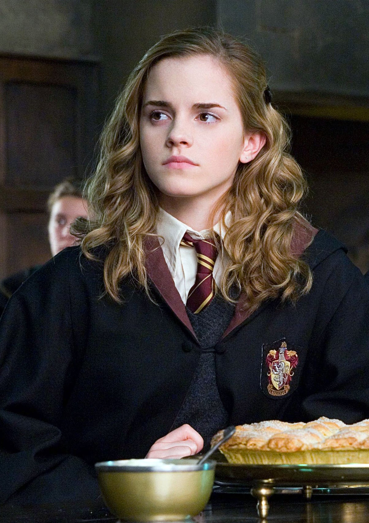 Emma Watson as Hermione Granger sits at a table in the Great Hall of Hogwarts