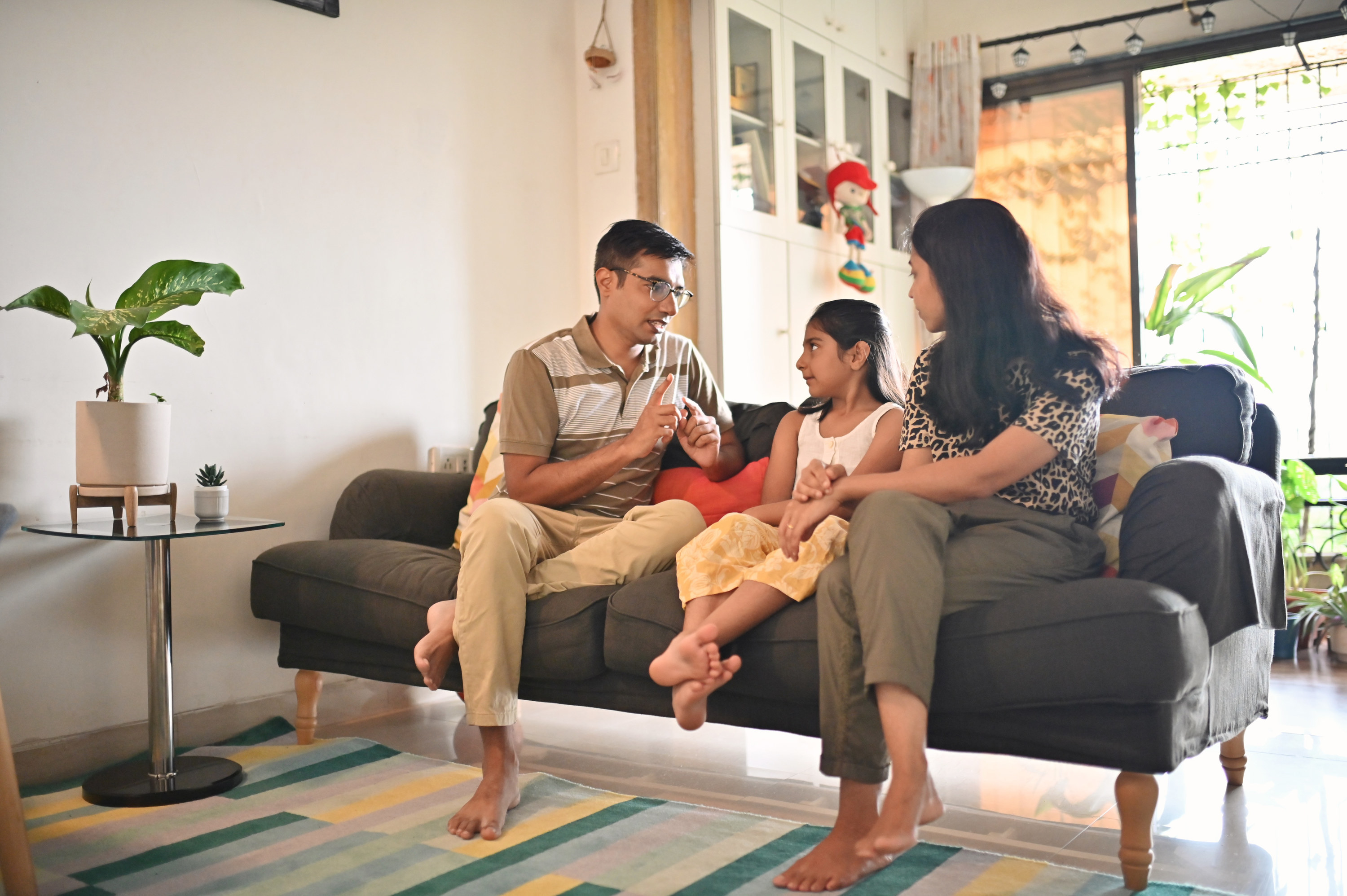 A mother and father talking to their young child inside their home