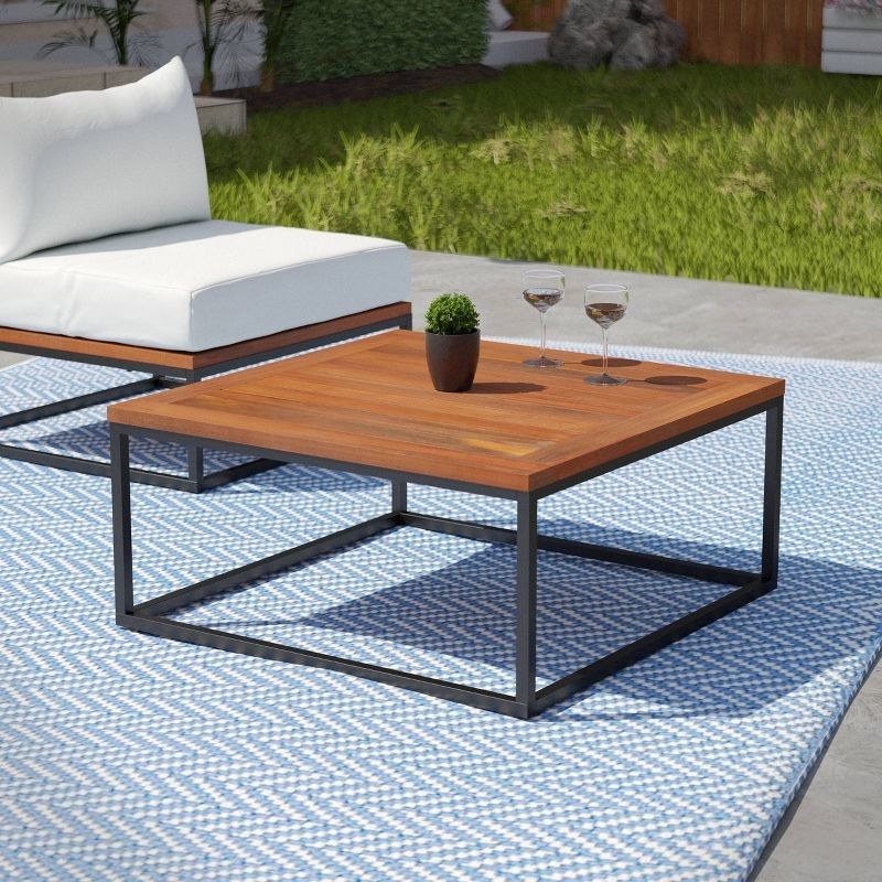 a wooden outdoor coffee table next to a chair with winecups