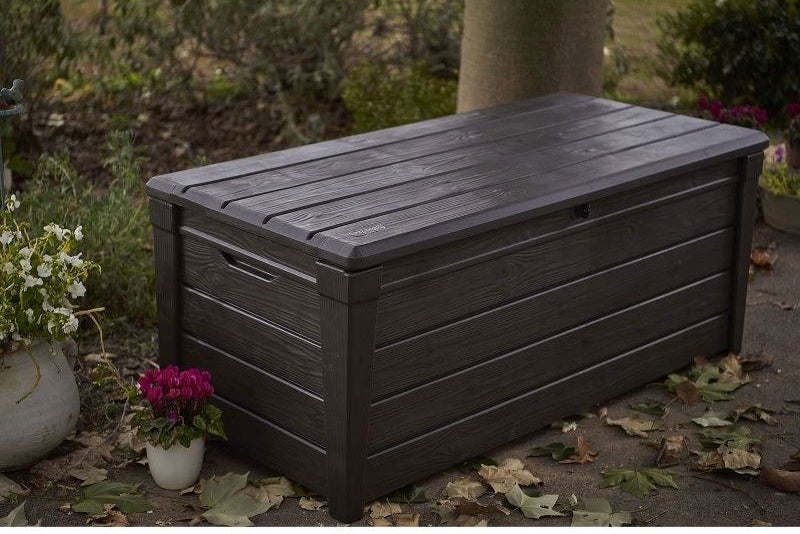 A brown wooden porch deck garden storage box bench laying outside
