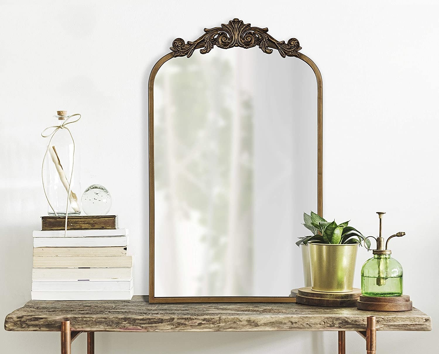 a baroque style mirror perched on a wooden console table