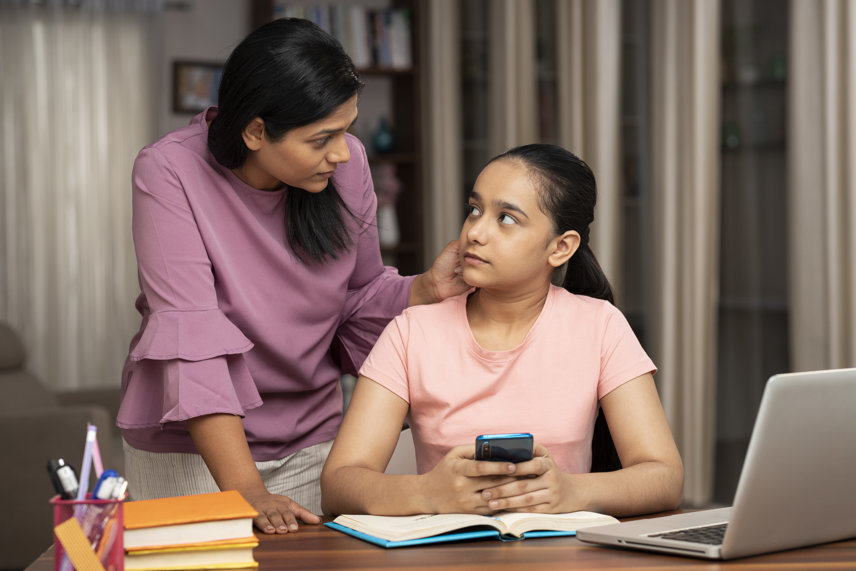 Mom looking at daughter while she&#x27;s on her phone