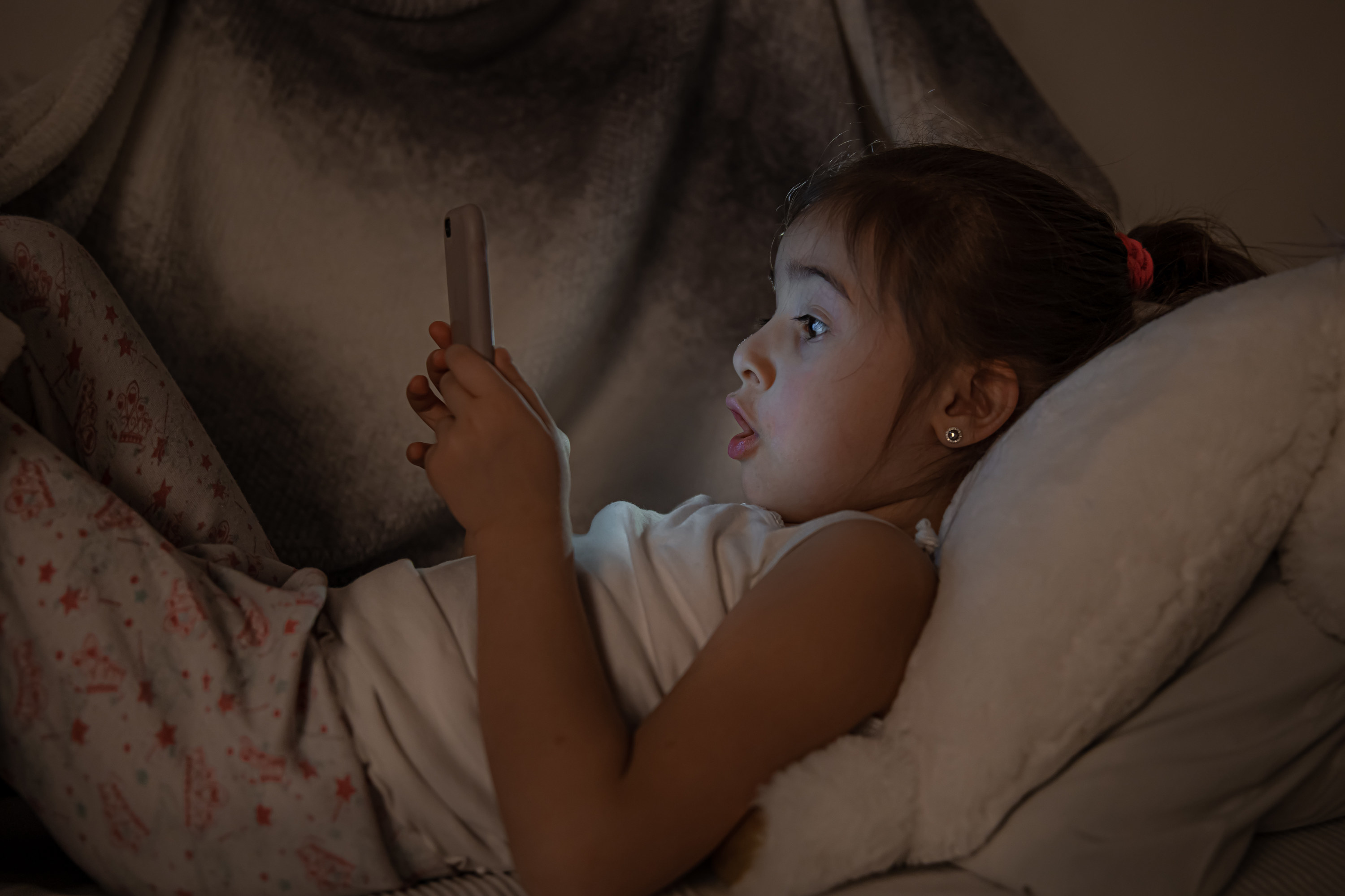 Little girl watching a smartphone in bed