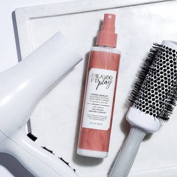 the pink and white spray bottle next to a blow-dryer and brush