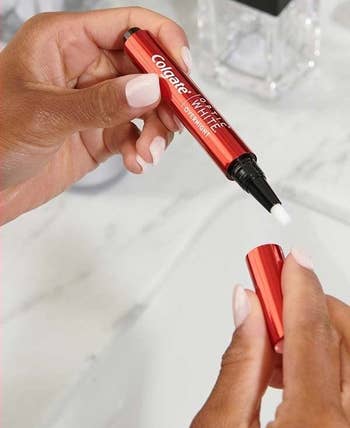 Model's hands holding the red tooth-whitening pen