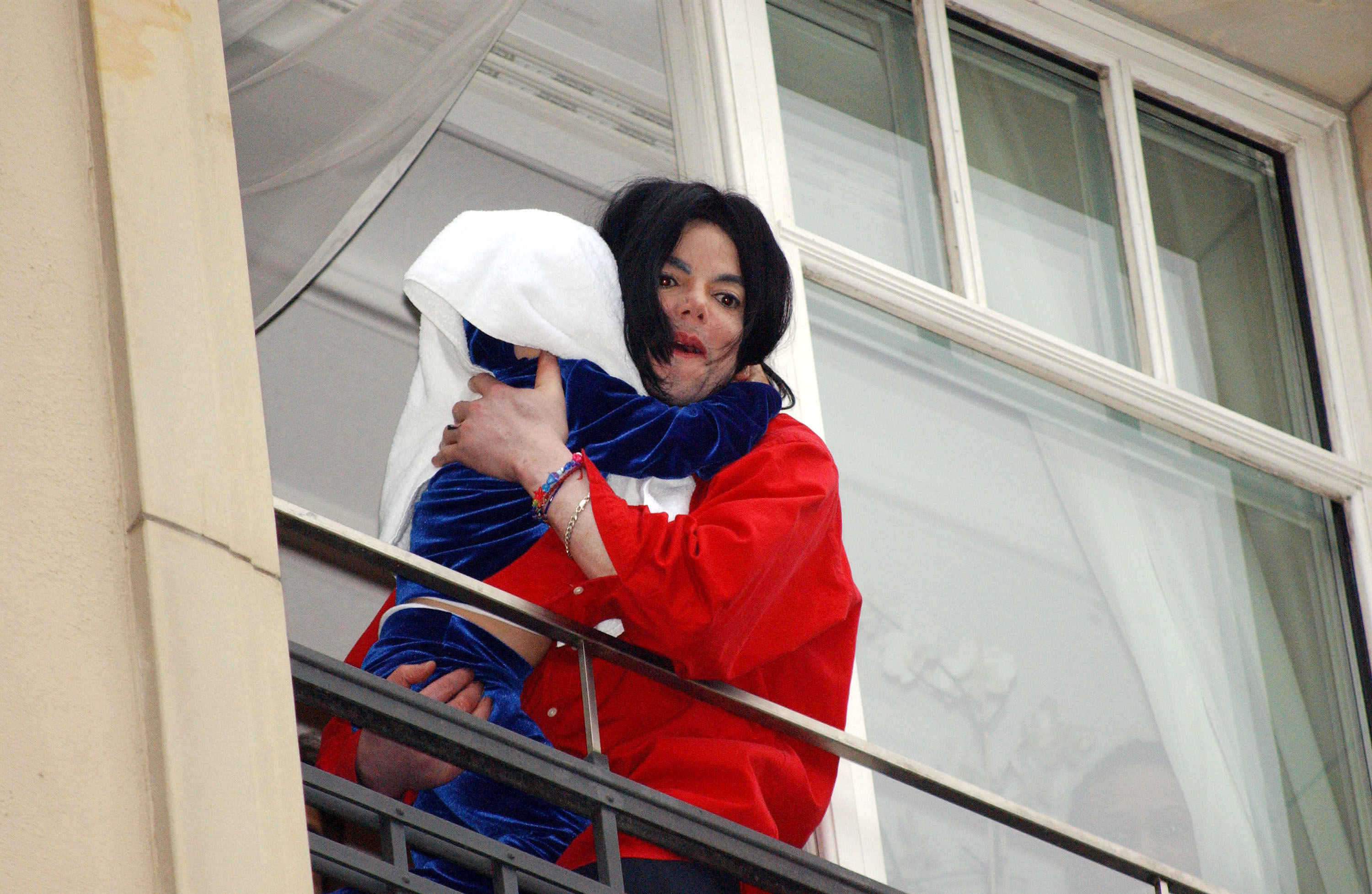Michael Jackson holds child that has a towel over his head