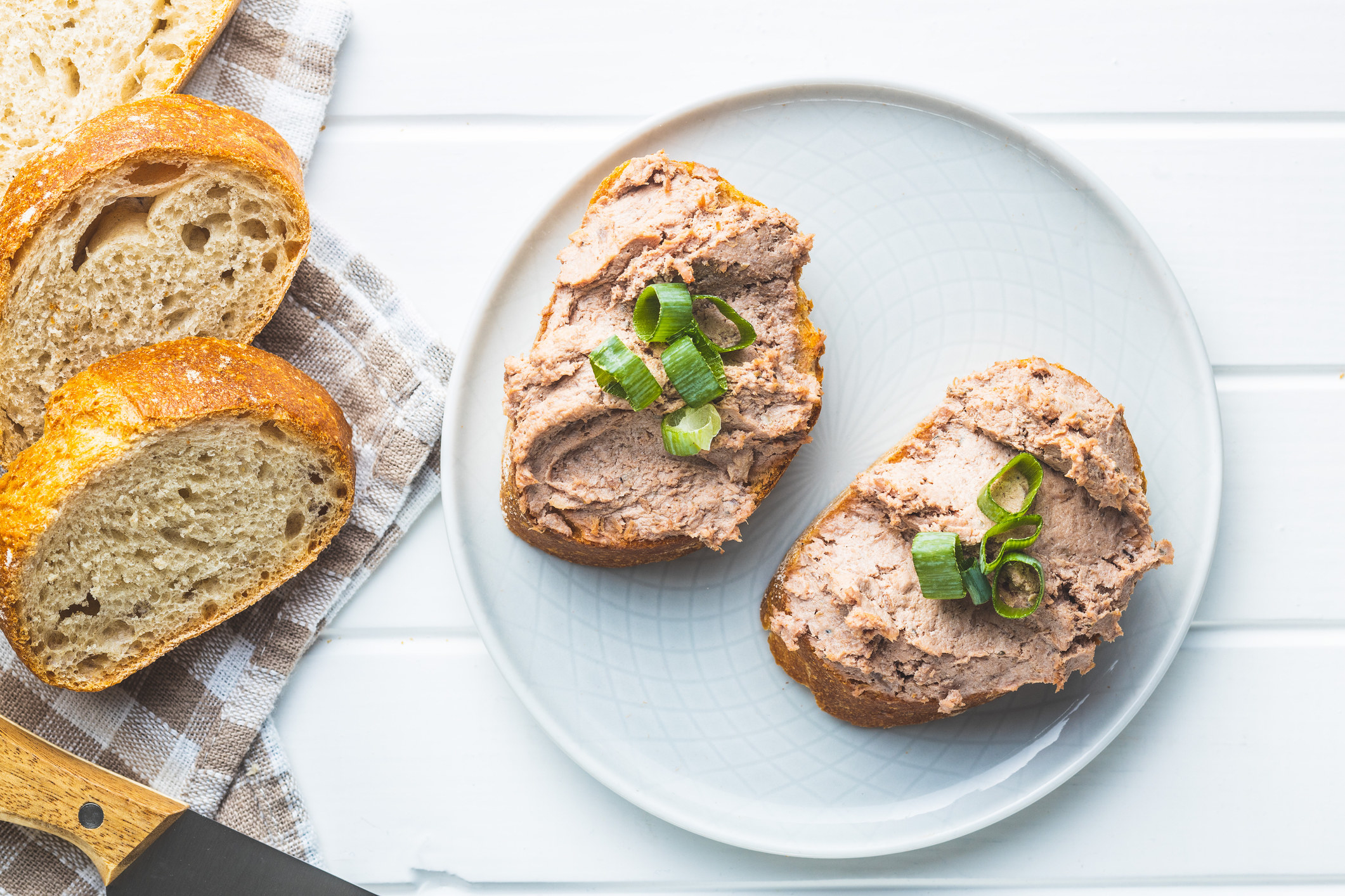 Liver pate on sliced baguette on plate.