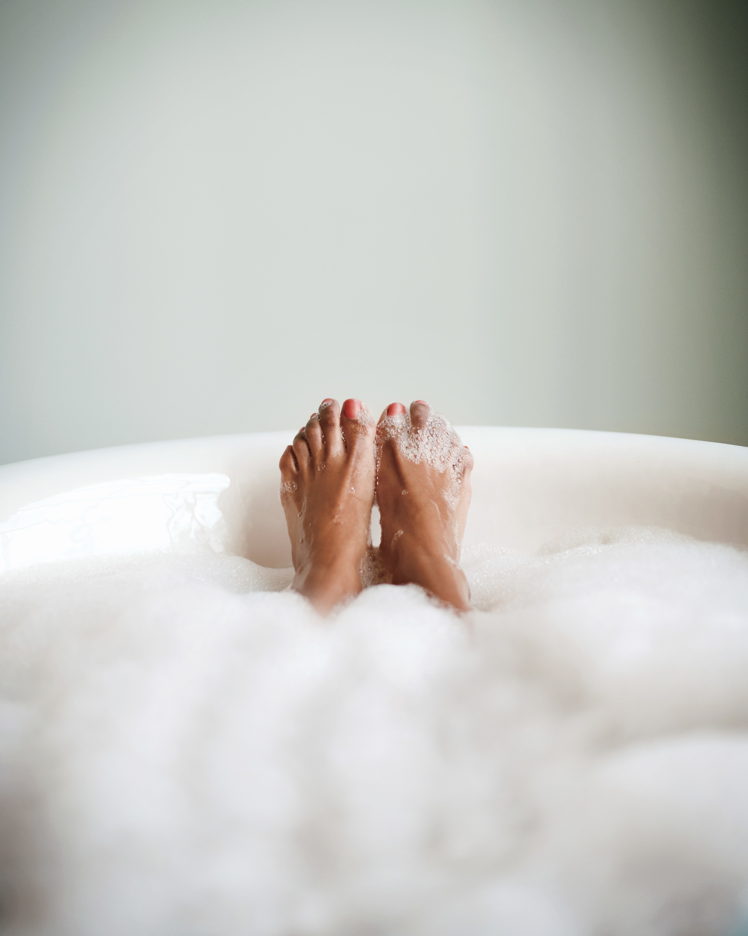A pair of feet sticking up out of a bubble bath