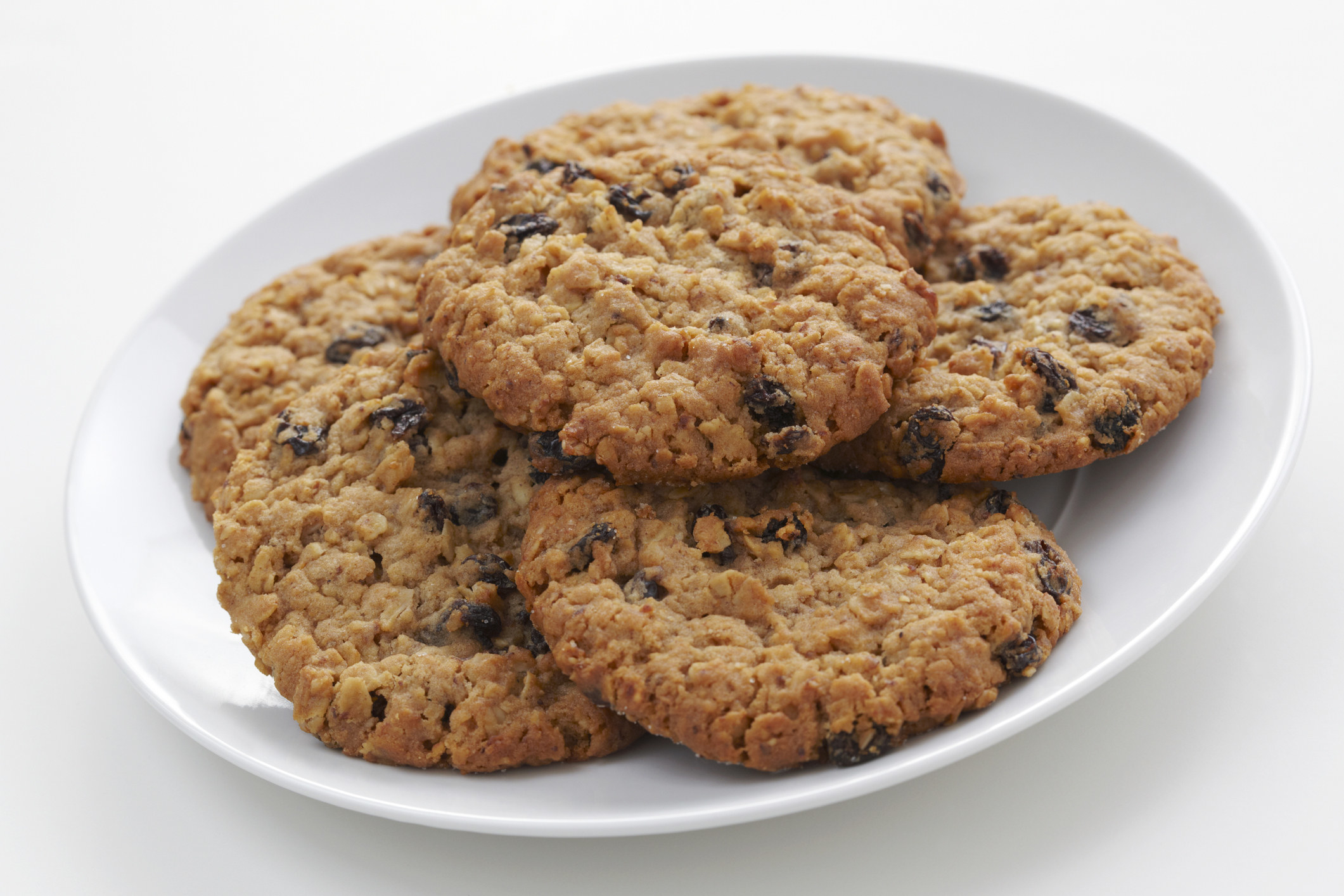 Six oatmeal raisin cookies in a white plate.