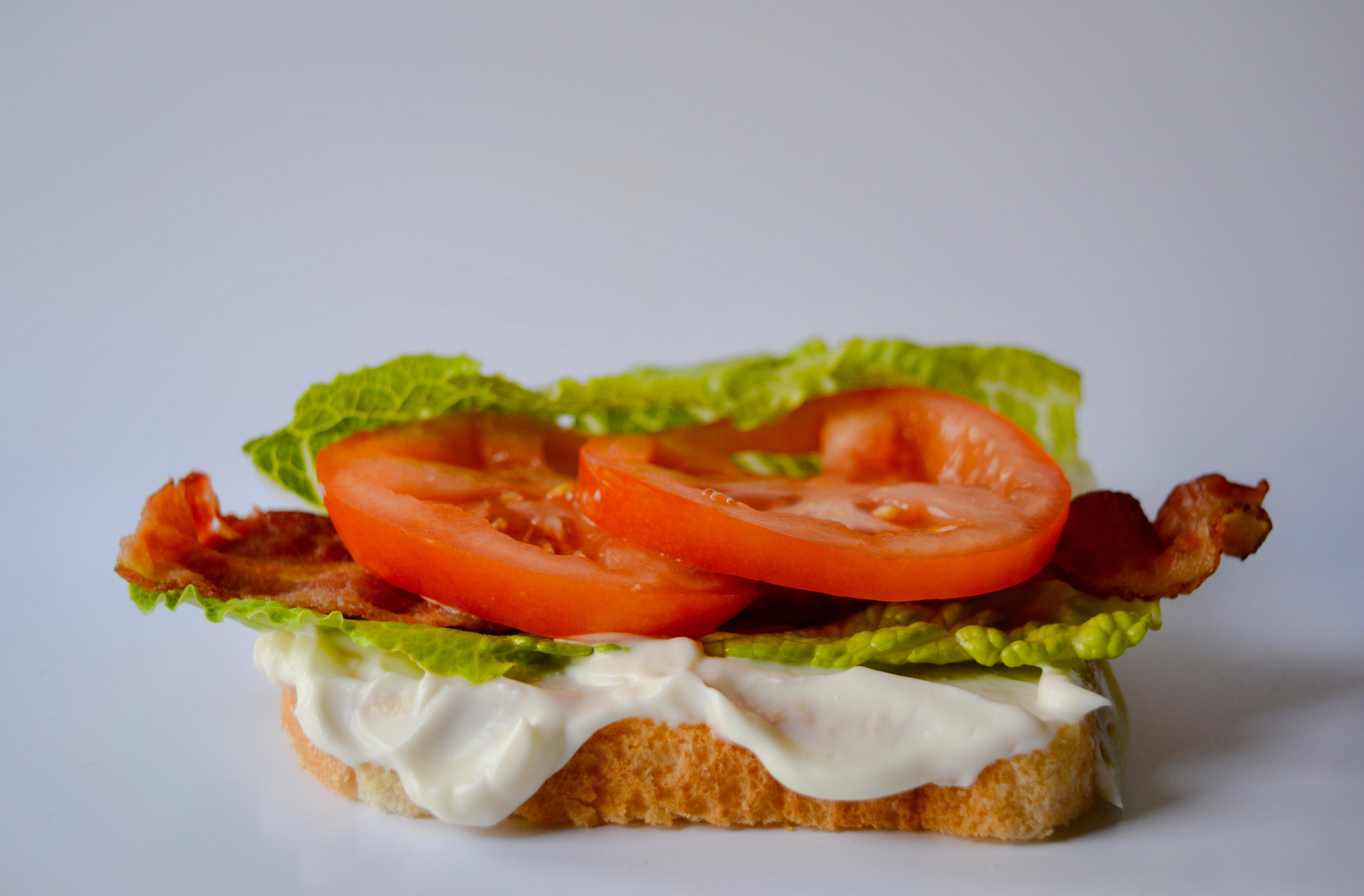 An open-face BLT sandwich with mayonnaise.