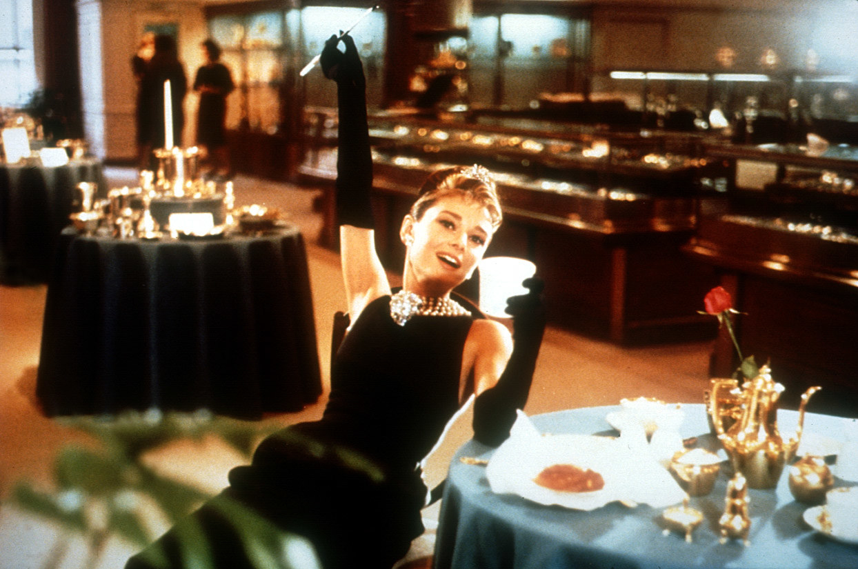 Audrey Hepburn drinks coffee at a table in Tiffanys