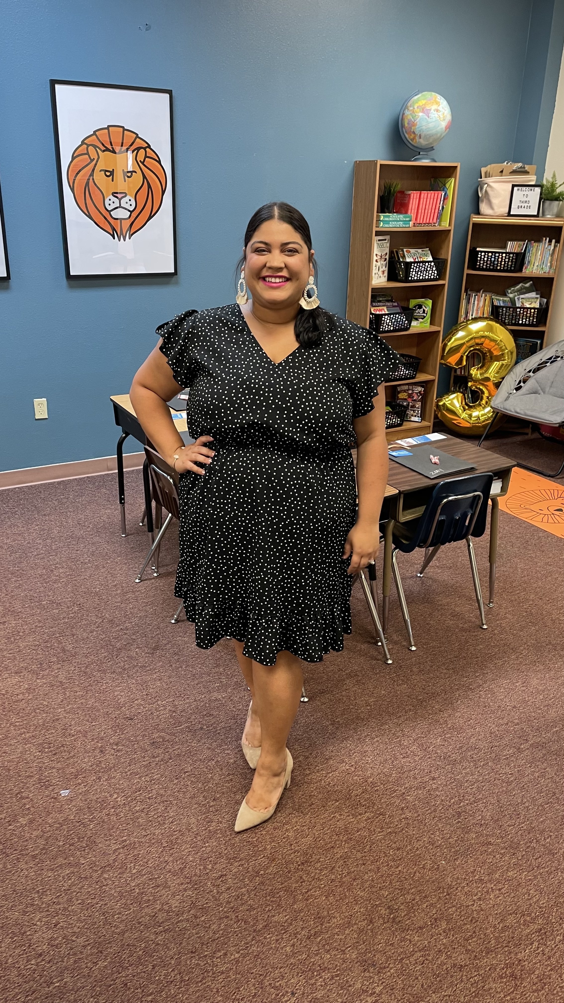 Sheila standing in a classroom wearing black polka-dotted dress