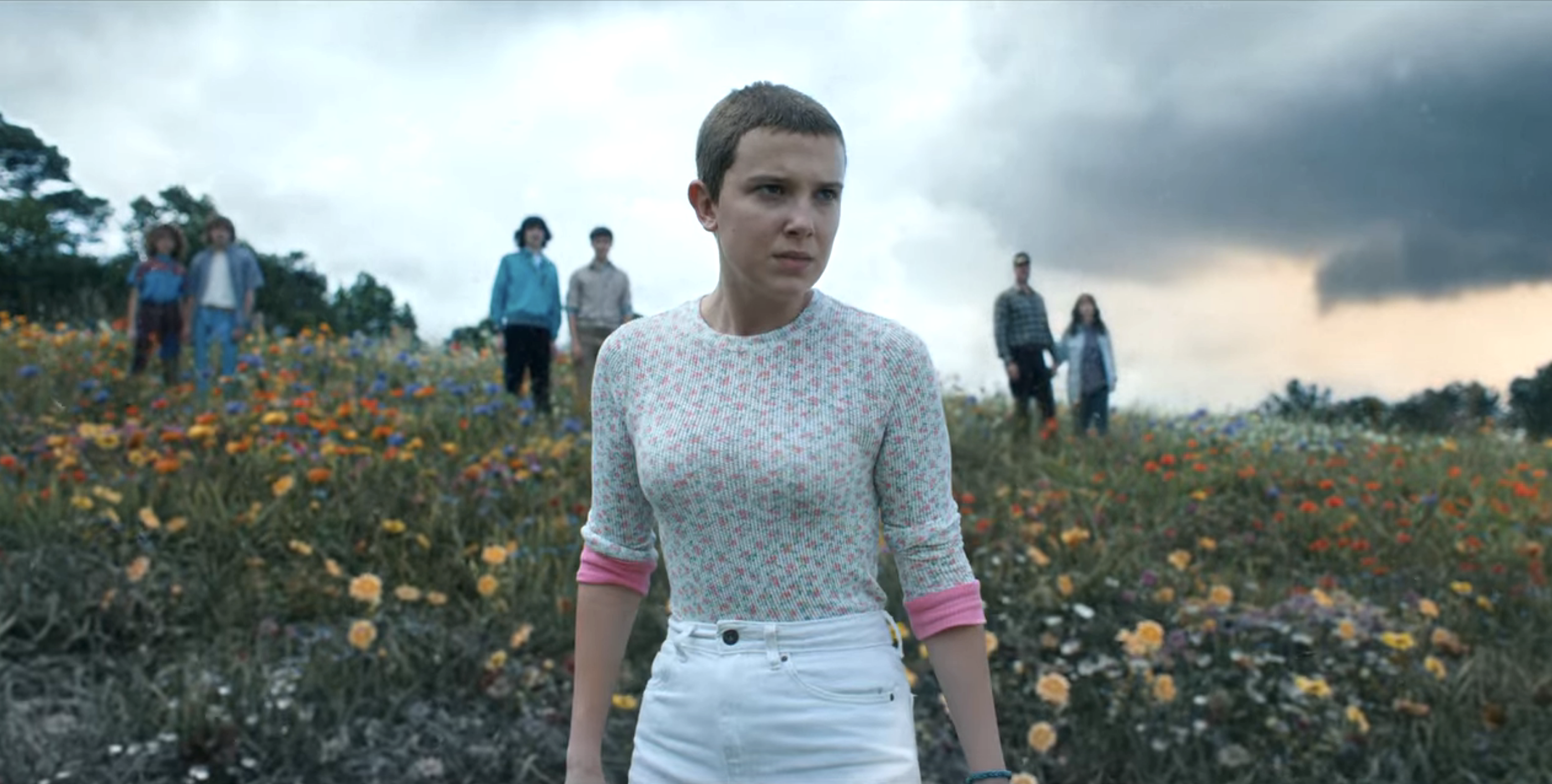 eleven in a field with her friends behind her