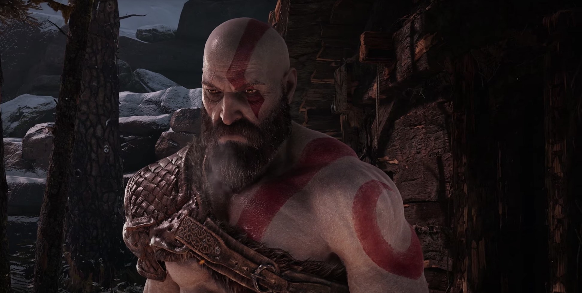 A gray-skinned man with red body paint and a beard stares solemnly in the distance