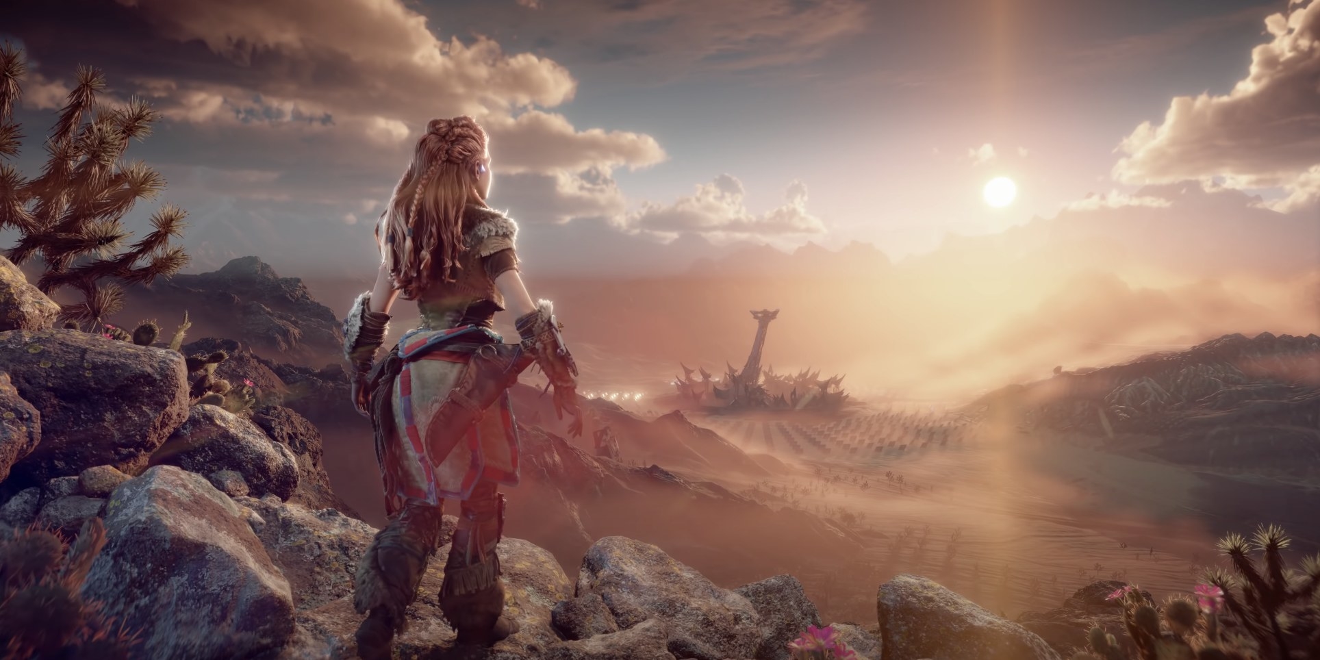 A red-haired woman stands on top of a large mountain, looking over a desert.