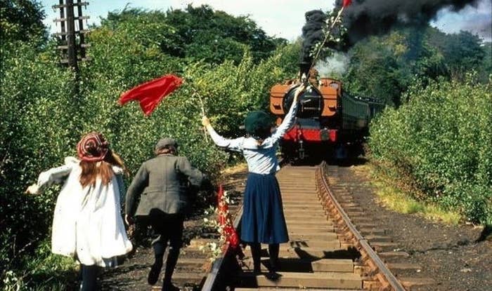 3 kids flagging down a train in The Railway Children using sheets on sticks