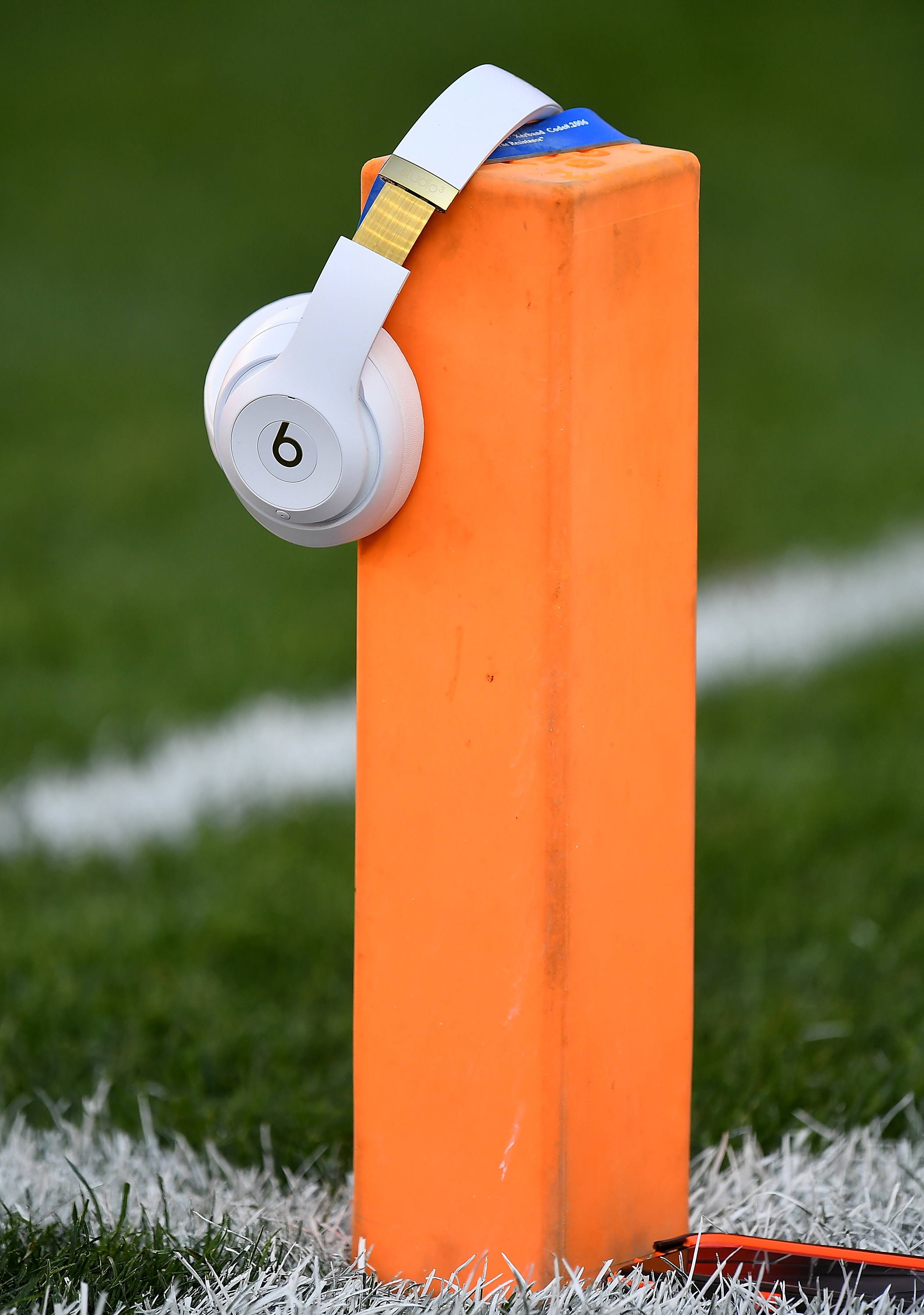 A pair of Beats by Dre headphones resting on a small pillar on a football field