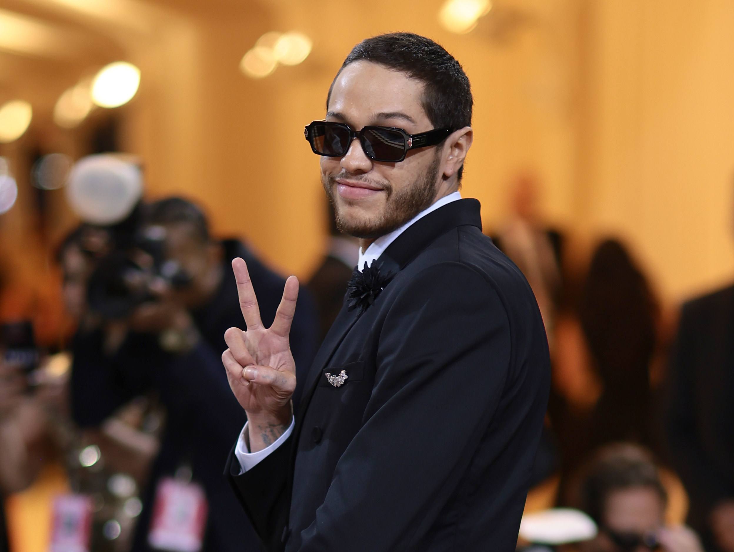 Pete Davidson making a peace sign a smiling at the camera