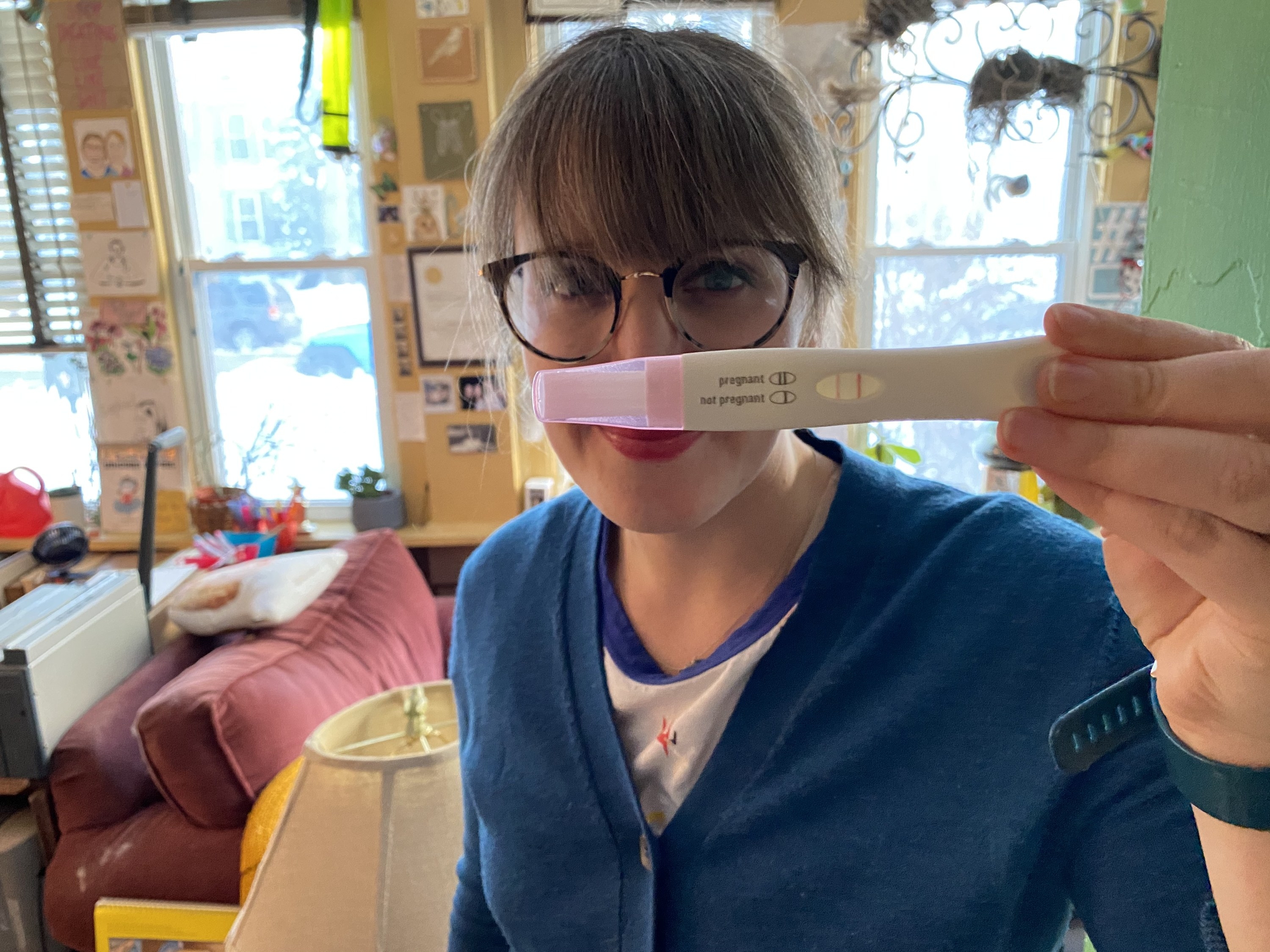 Story author, Sophie, holding up a positive pregnancy test and smiling
