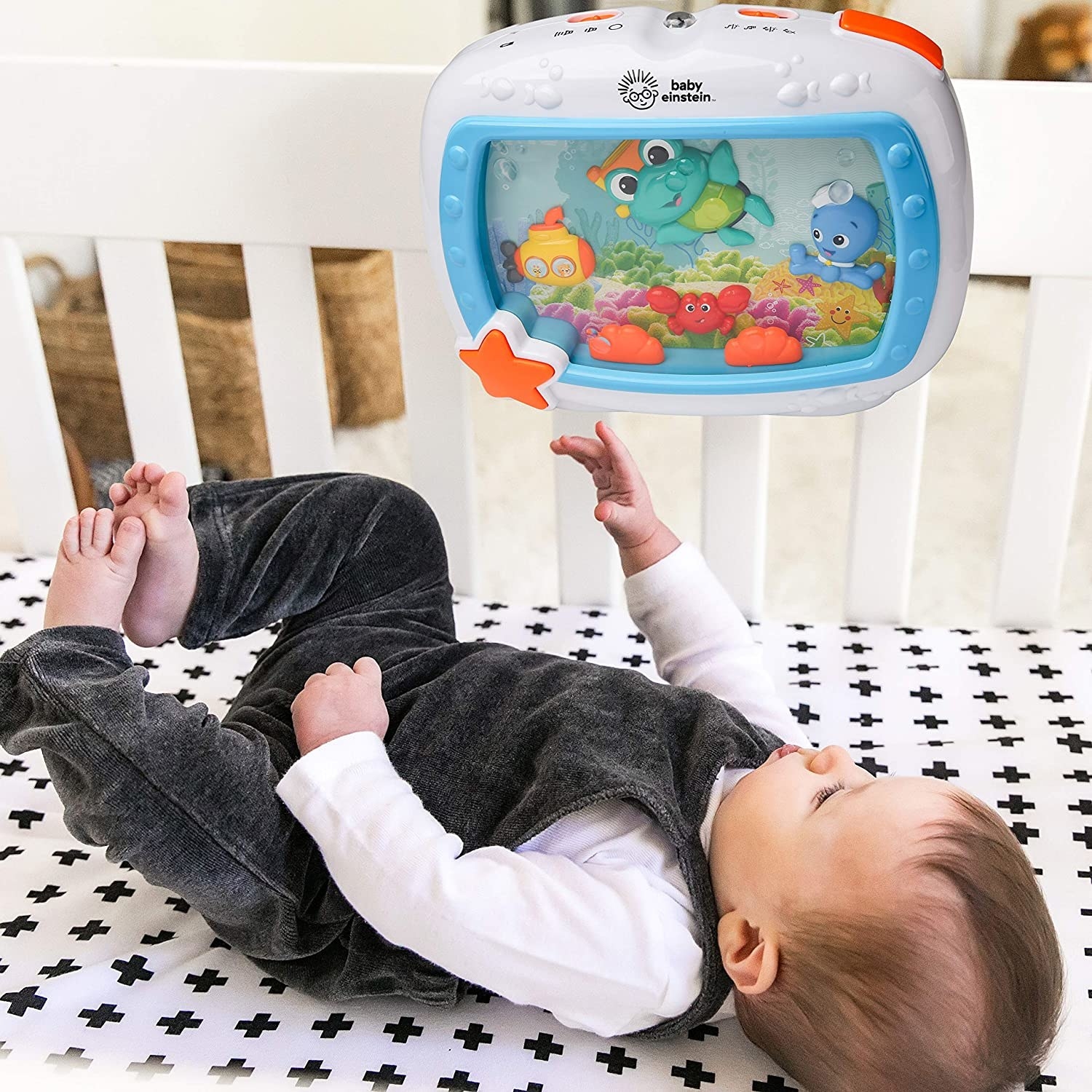 baby in crib looking at the attached aquarium toy
