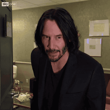 GIF of Keanu Reeves holding his hands to his heart then out