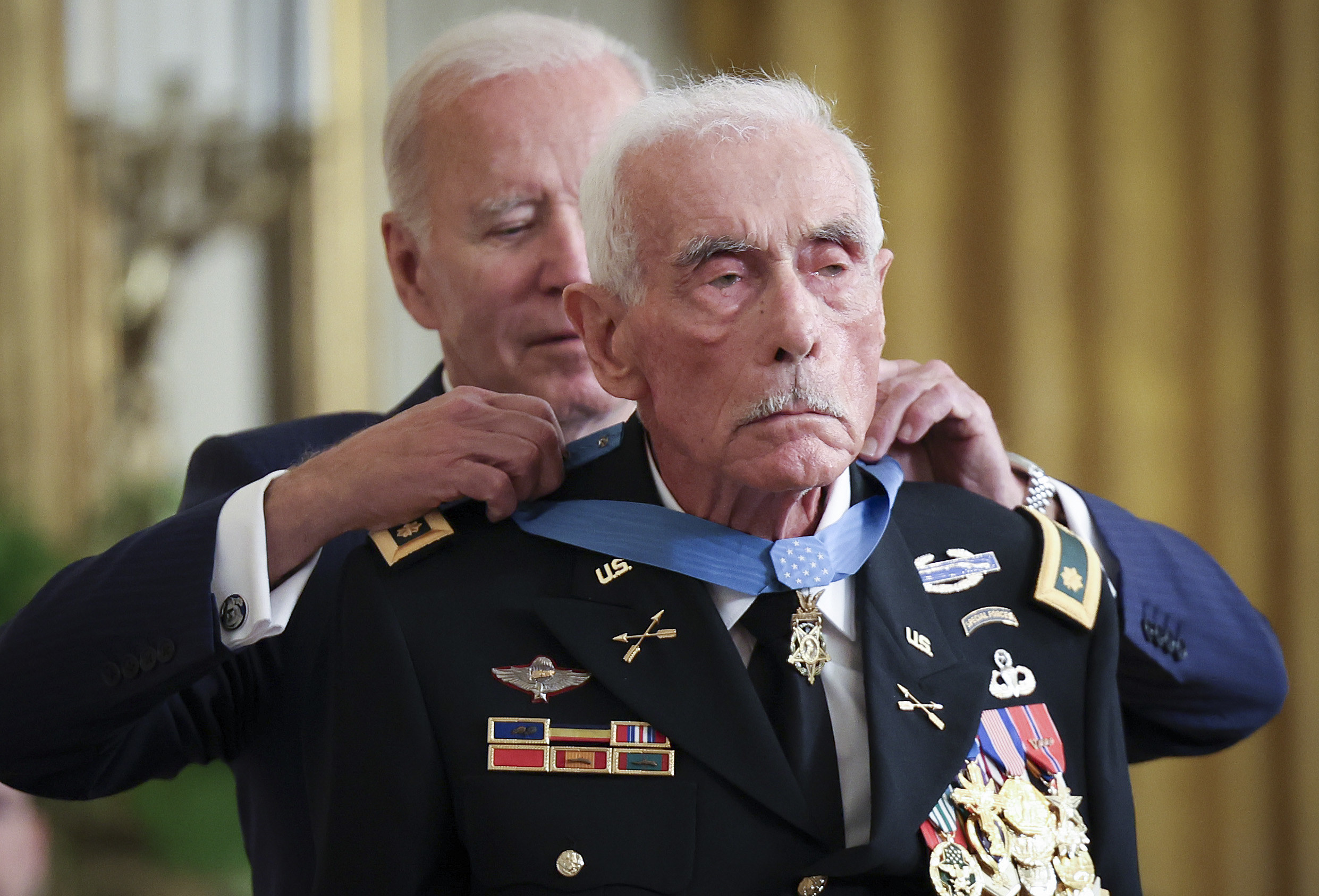 President Joe Biden putting a medal around an older military man&#x27;s neck