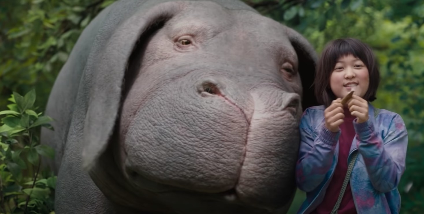 Okja character cuddling into a young girl