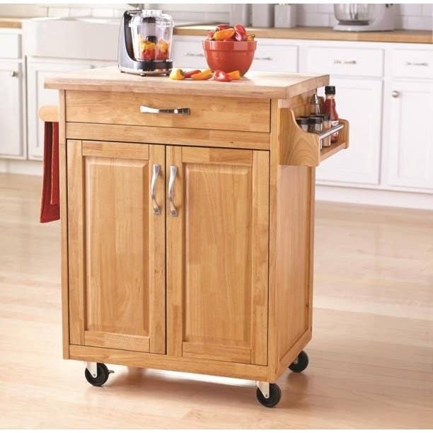 a wooden kitchen cart with blender and bowl on top and sauces on the side