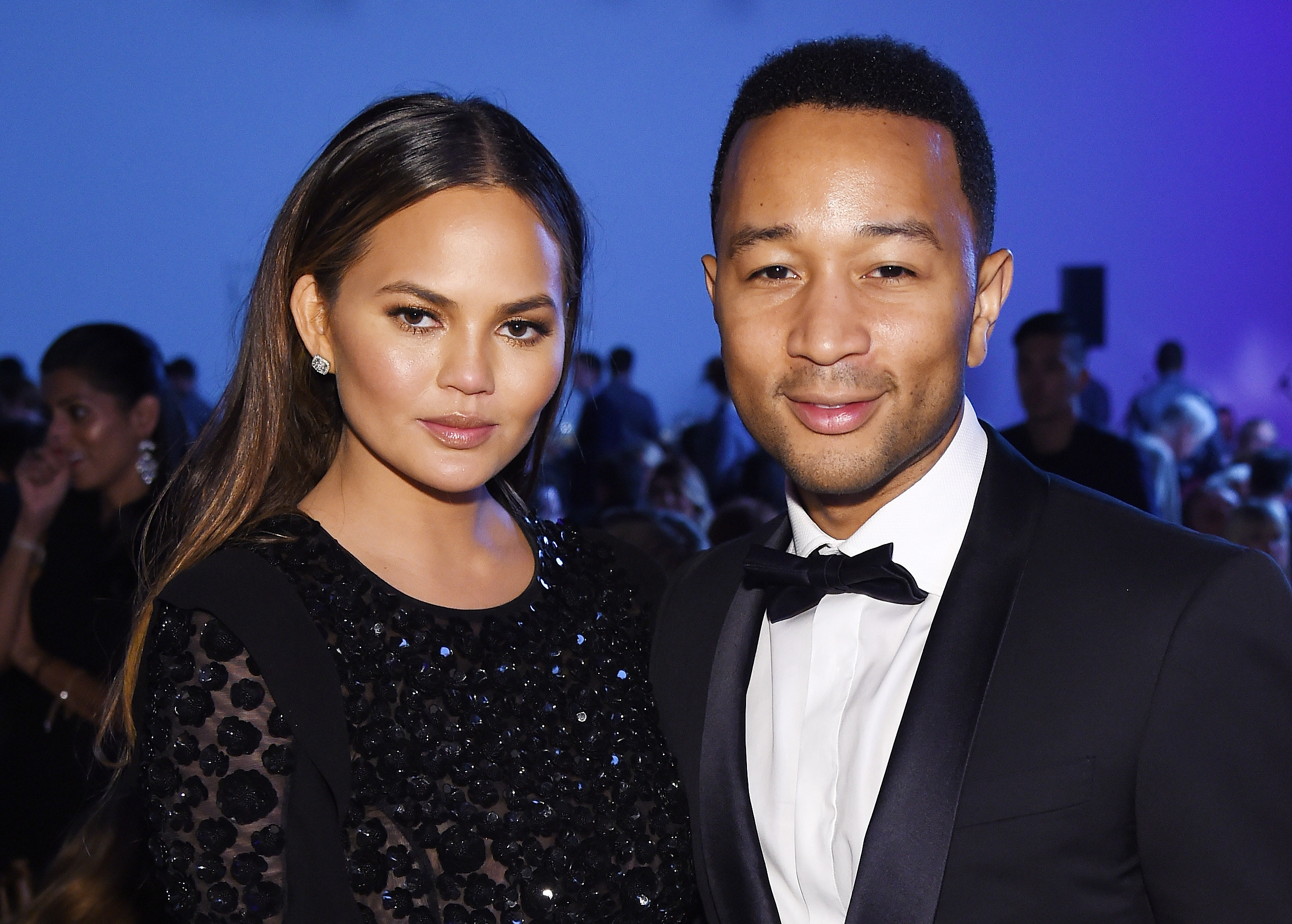 Chrissy Teigen in a sparkly black dress and John Legend in a tuxedo posing for the camera