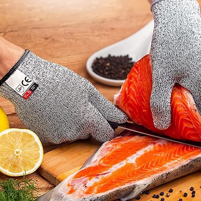 Someone wearing the grey gloves and slicing salmon into filets