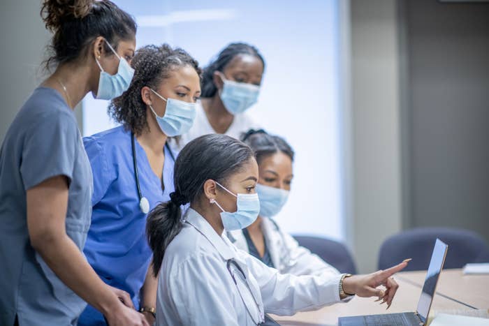 nurses gathered around looking at a laptop