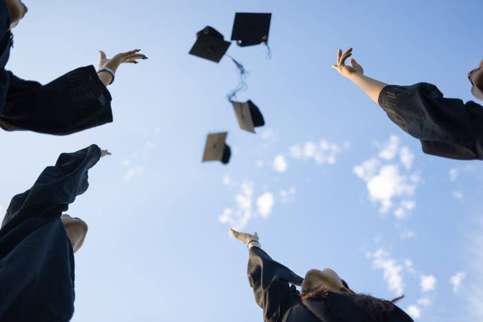 students tossing graduation caps into the air