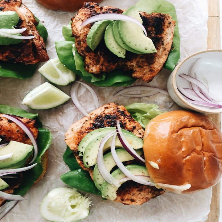 Seared salmon burgers with lettuce, onion, and avocado.