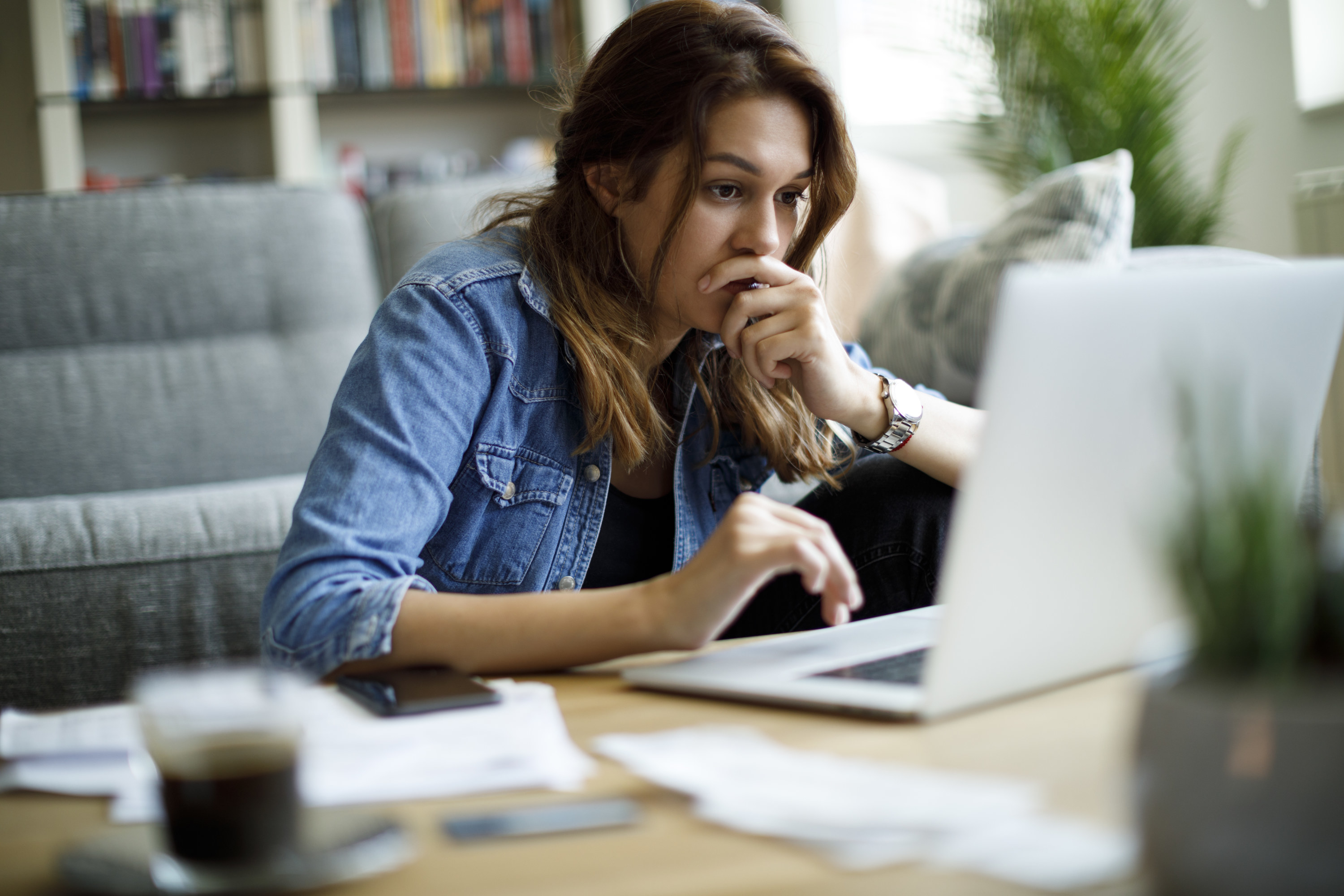 A stressed-looking young woman staring at a laptop