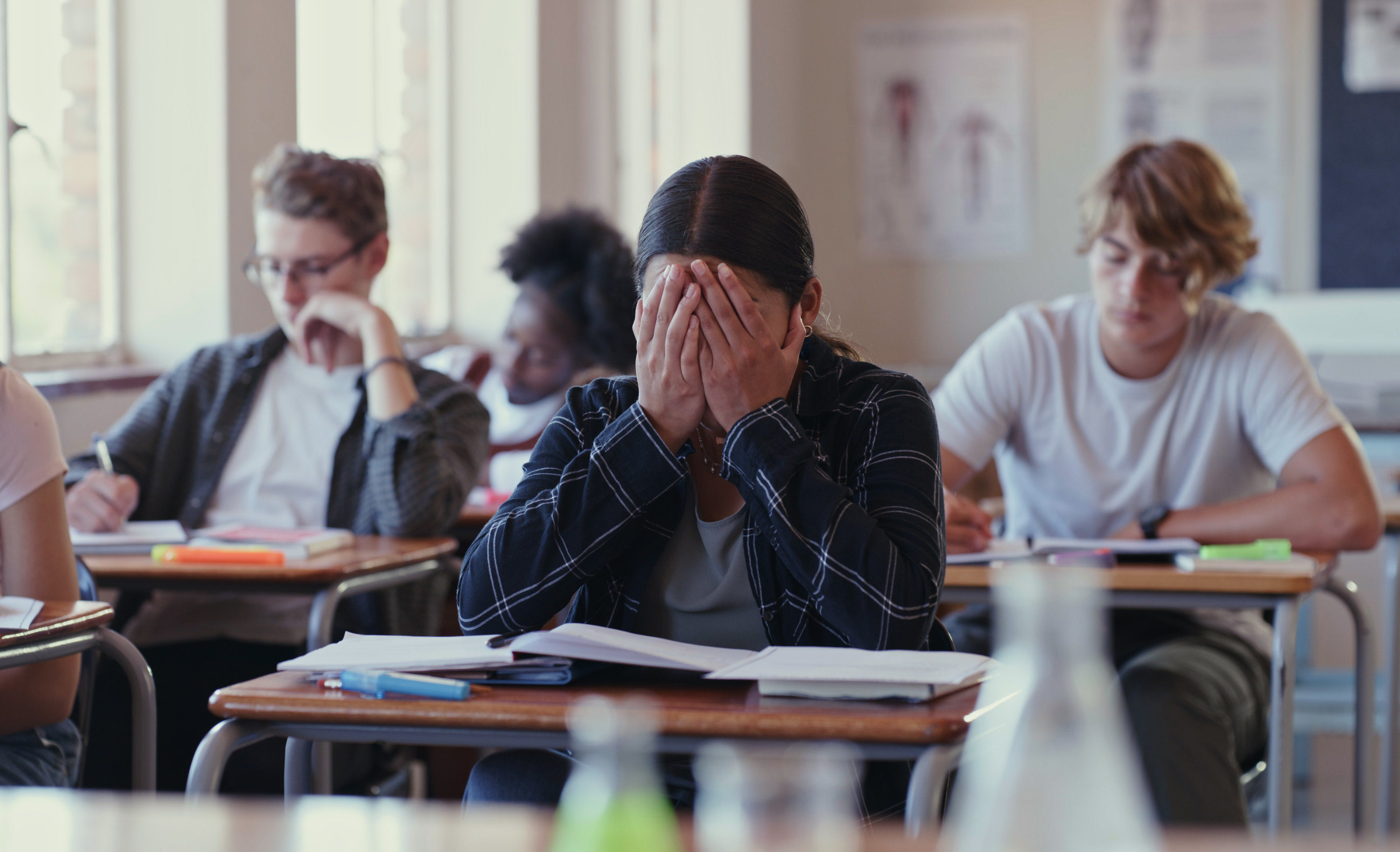 Stressed student in class with their hands over their face