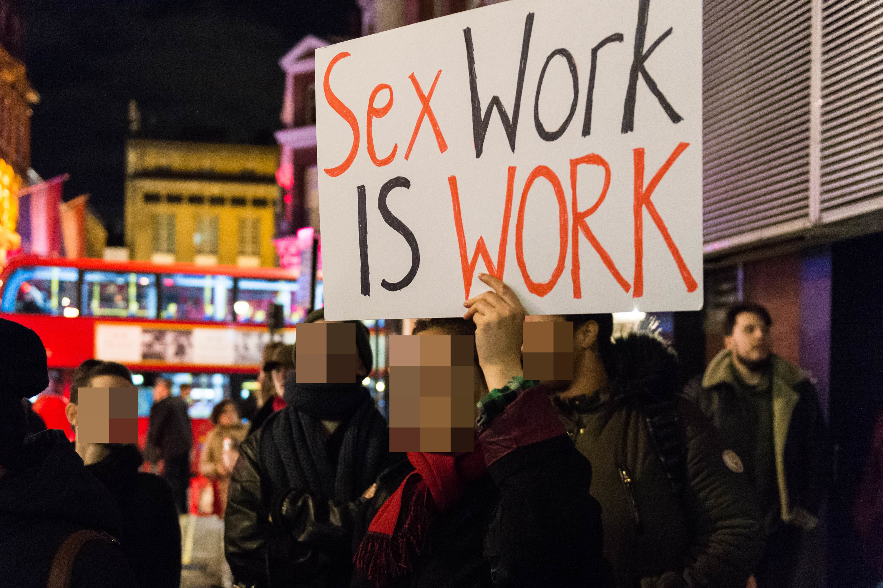 Someone holding up a sign that says &quot;Sex work is work&quot;