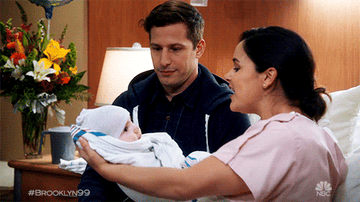 Amy Santiago hands a baby boy to Jake Peralta