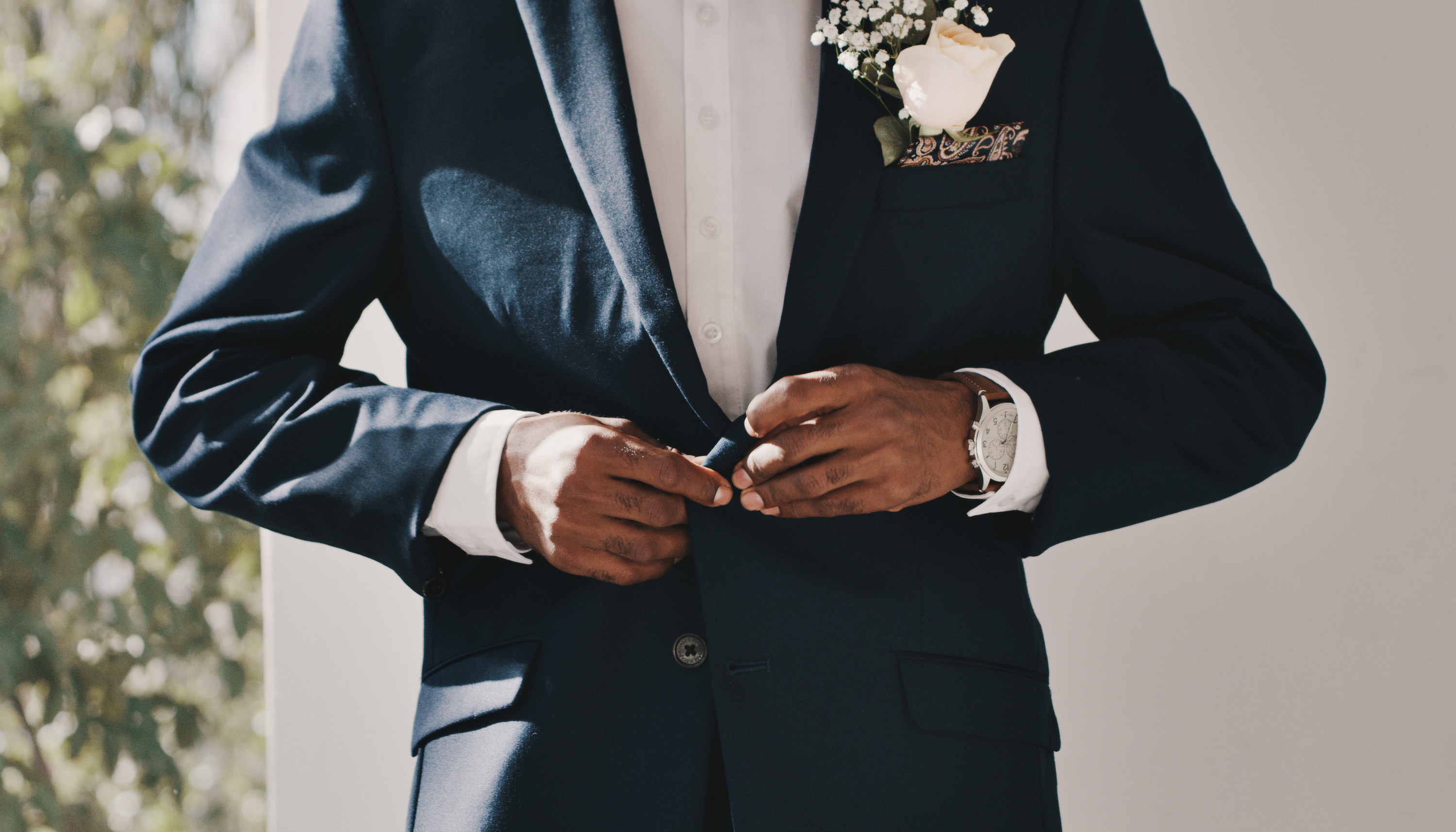 man buttoning top button on tuxedo