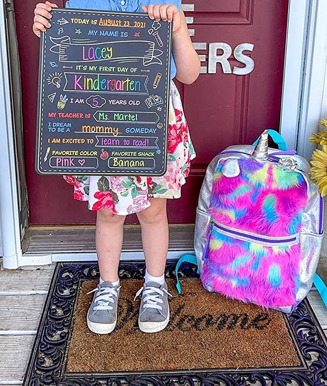 reviewer's photo of their child holding up the chalkboard sign