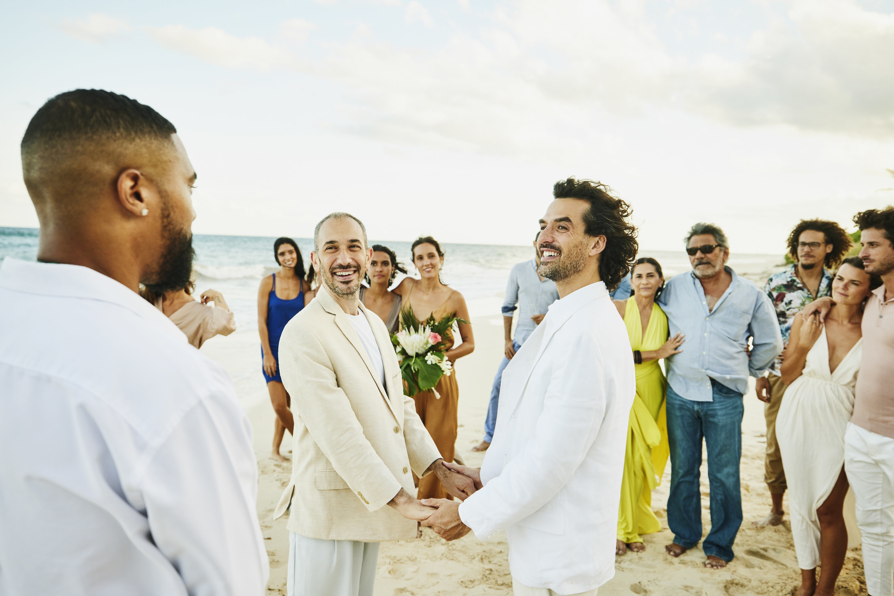 Two men holding hands getting married on the beach