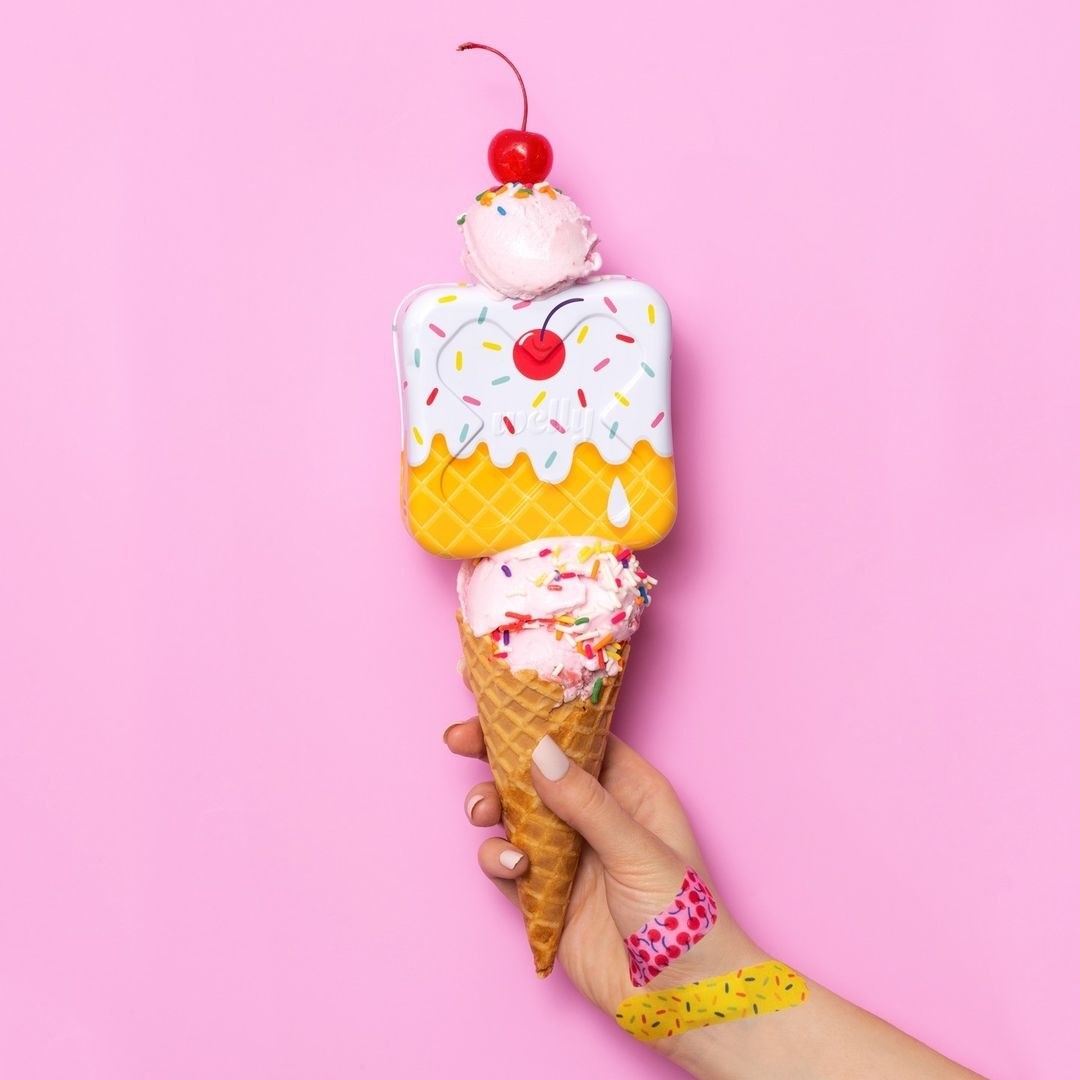 a hand with the colorful bandages holding an ice cream cone that matches the bandage container