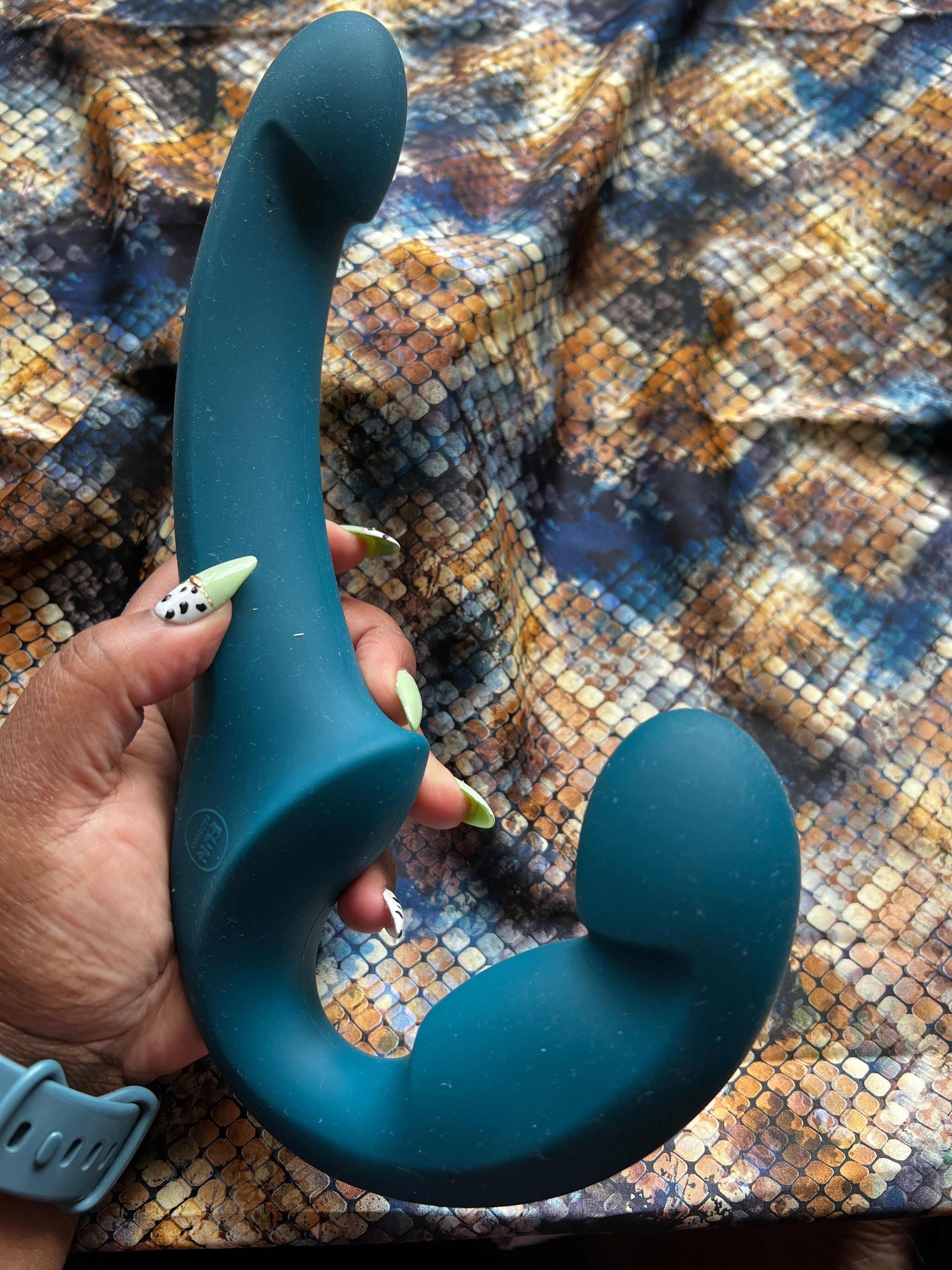 Hand holding teal dual-ended dildo