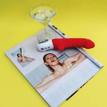 Red textured vibrator on magazine next to martini glass