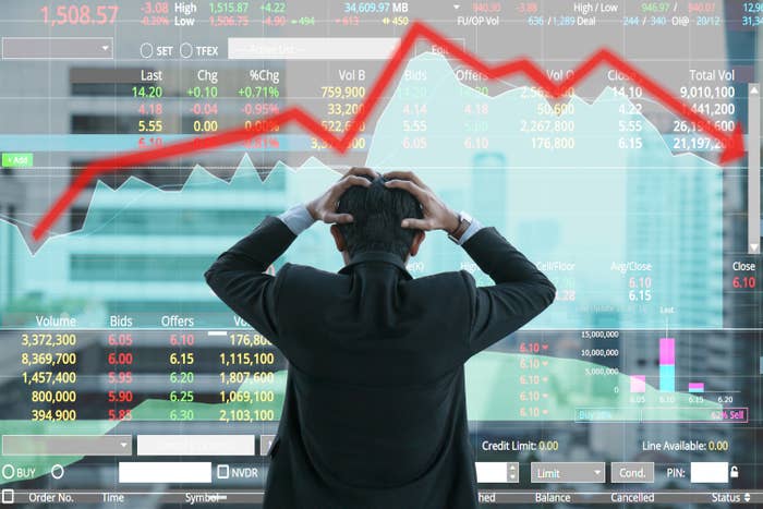 stock trader holding his head looking at a chart that shows prices going down
