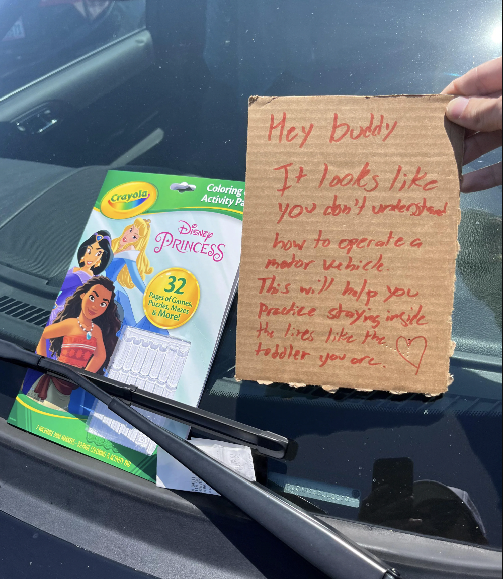 coloring book and sign on someone's windshield saying the book will help them stay inside lines
