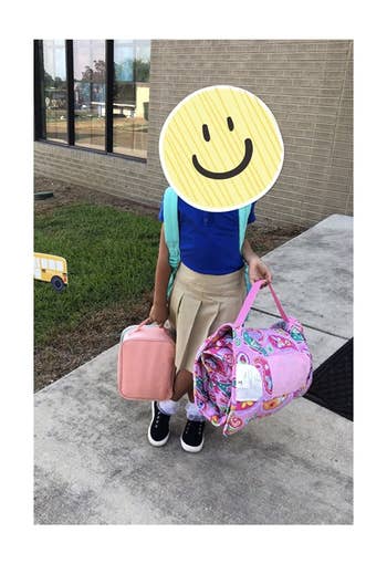 reviewer's photo showing their child carrying the rolled up nap mat
