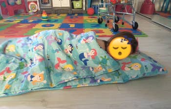 reviewer's photo of their child in the mermaid print nap mat