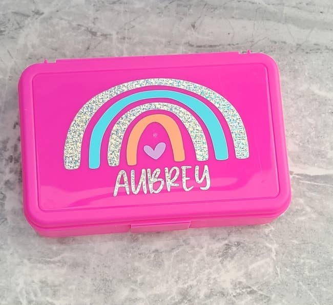 A personalized pencil case with a rainbow design on the lid