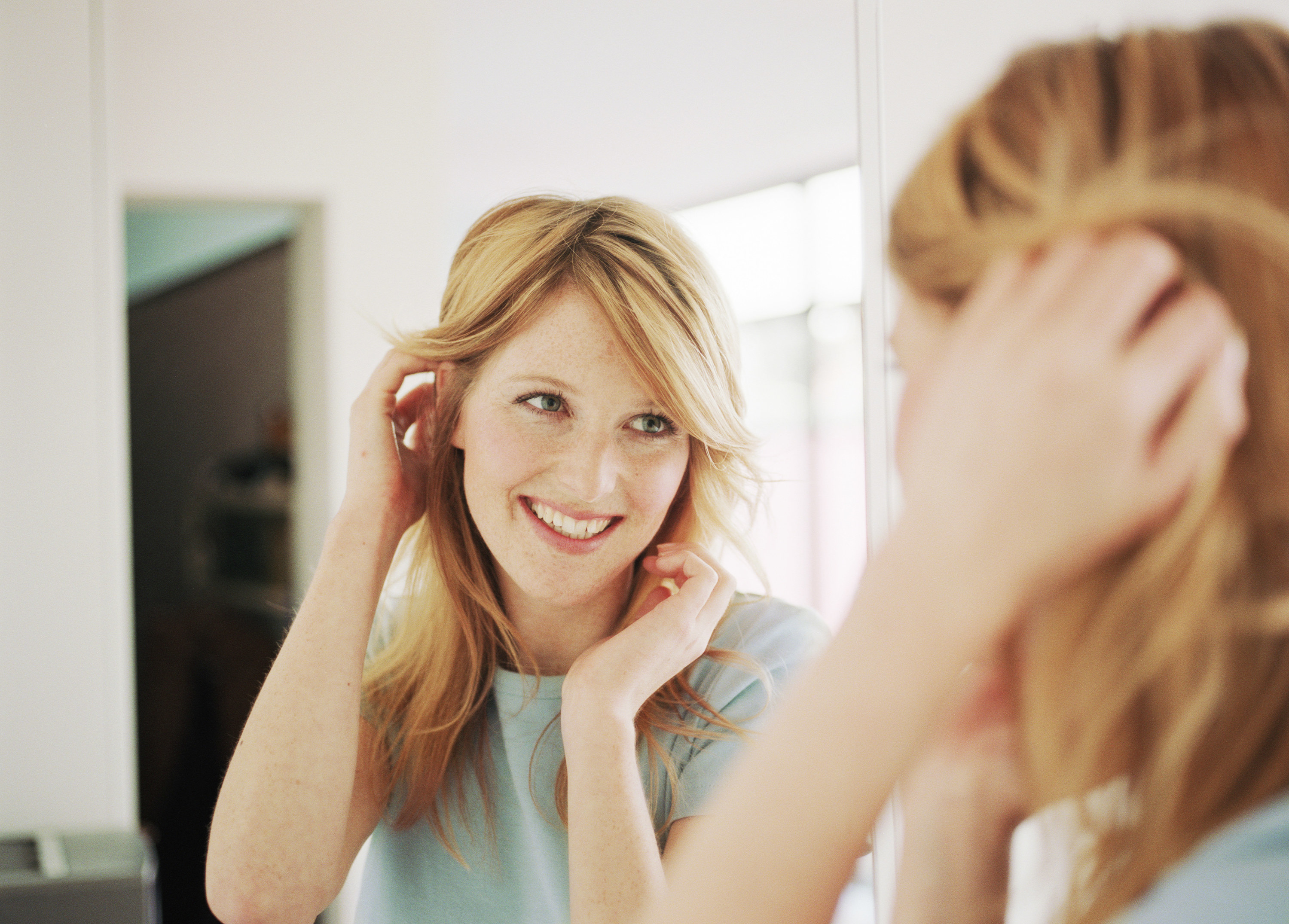 A woman smiles as she stares at herself in the mirror